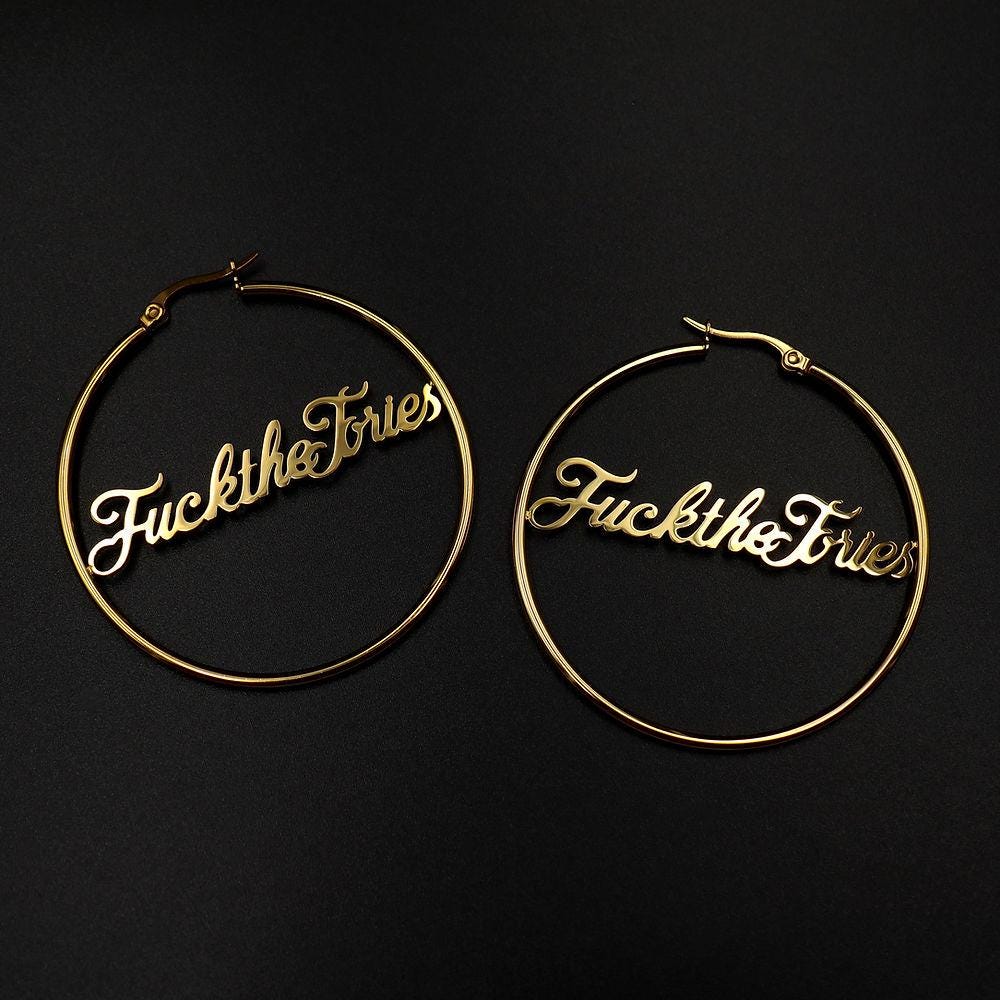 A pair of ‘Fuck The Tories’ hoop earrings by Topple & Burn – bold political jewellery made from surgical steel with gold or silver plating options.