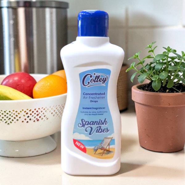 Colley Concentrated Air Freshener Drops bottle labeled 'Spanish Vibes' on a kitchen counter with fruits and a plant.